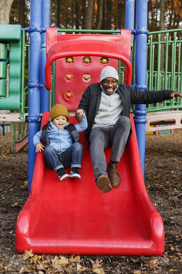 Father and son on playground slide in park
