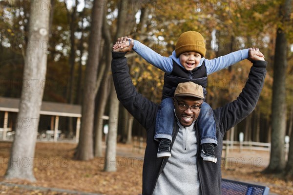 Father carrying son on  shoulders in park