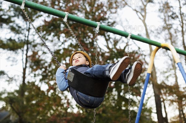 Mixed Race boy on playground swing