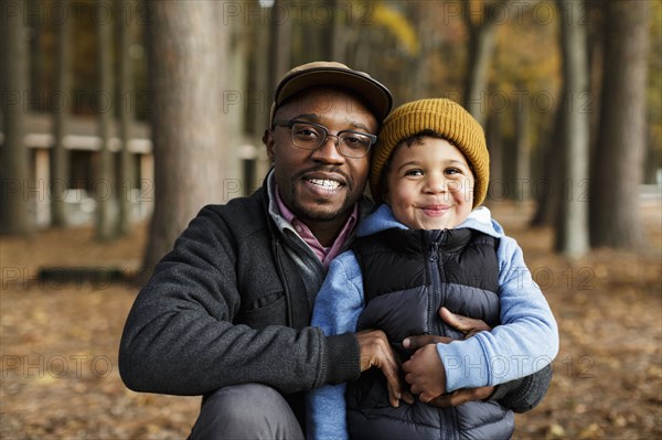 Portrait of smiling father and son hugging in park