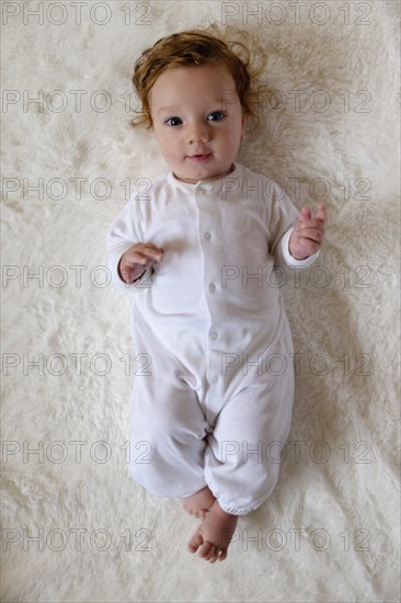 Portrait of Caucasian baby boy laying on white fur blanket