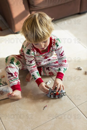 Caucasian boy sitting on floor in pajamas playing with toys