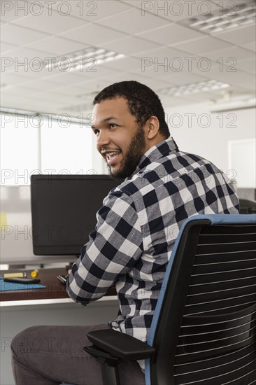 Smiling Mixed Race man using computer in office