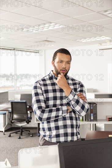 Pensive Mixed Race man standing in office