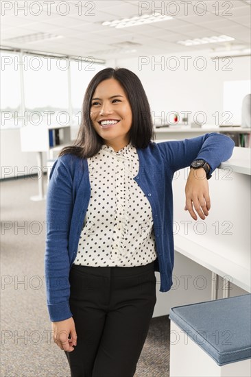 Smiling Pacific Islander woman standing in office