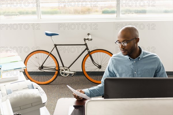 African American man reading paperwork in office