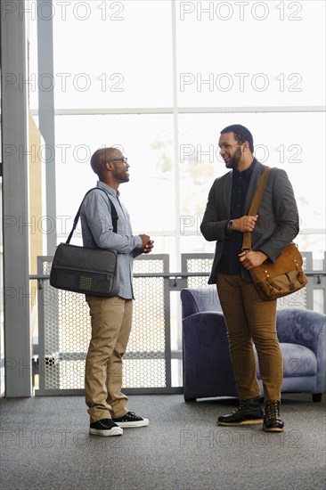 Men carrying briefcases talking in lobby