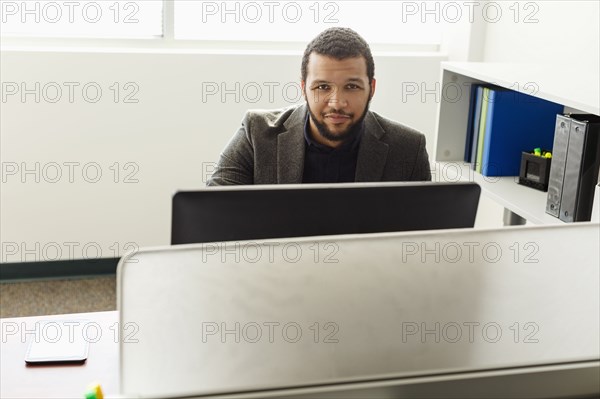 Smiling Mixed Race man using computer in office