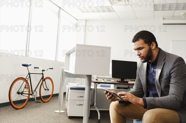 Mixed Race man using digital tablet in office