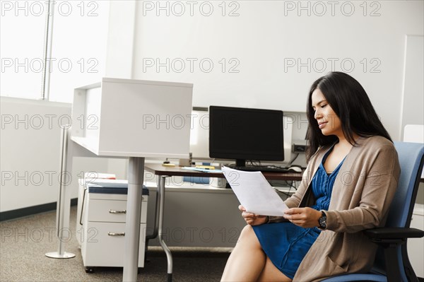 Pacific Islander woman reading paperwork in office