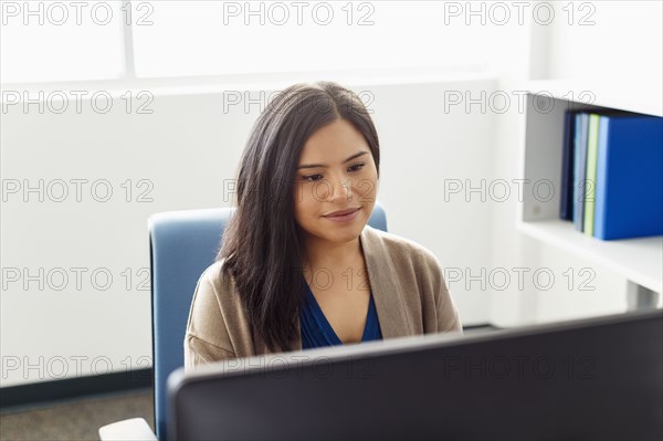 Pacific Islander woman using computer in office