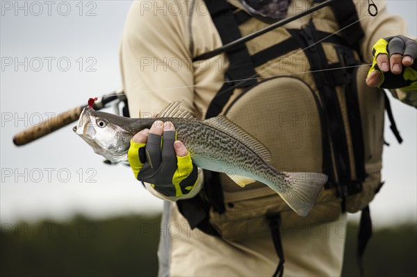 Caucasian man holding fishing rod and fish