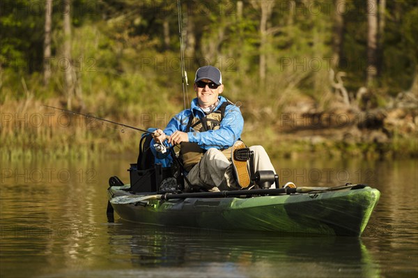 Caucasian man pedaling in kayak and fishing