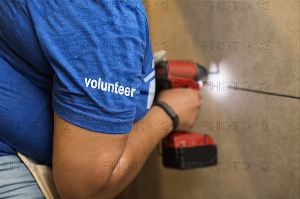 Volunteer black woman drilling wall