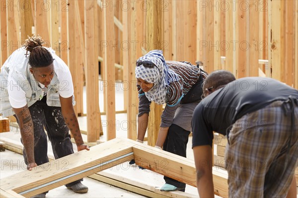 Volunteers lifting wooden frame at construction site