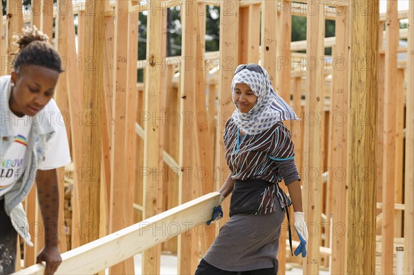 Volunteers carrying lumber at construction site