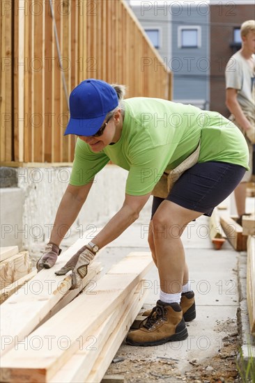 Caucasian woman lifting lumber at construction site