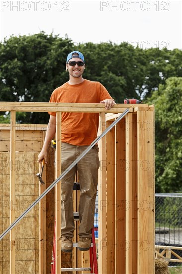 Portrait of Caucasian man standing on ladder at construction site