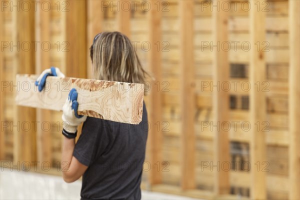 Caucasian woman carrying lumber at construction site