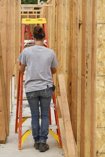 Caucasian woman pushing ladder at construction site