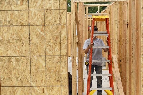 Caucasian woman carrying ladder at construction site