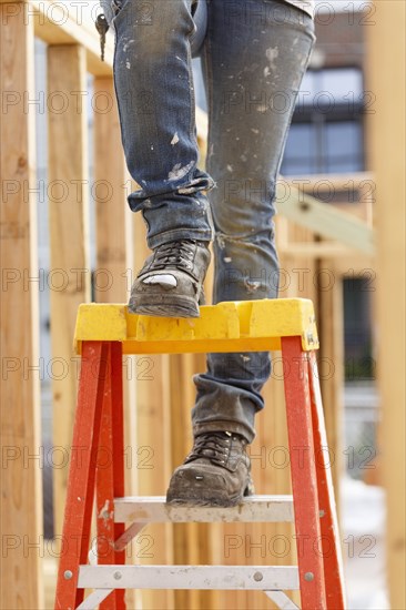 Legs of Caucasian woman on ladder at construction site