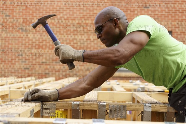 Black man hammering nail at construction site