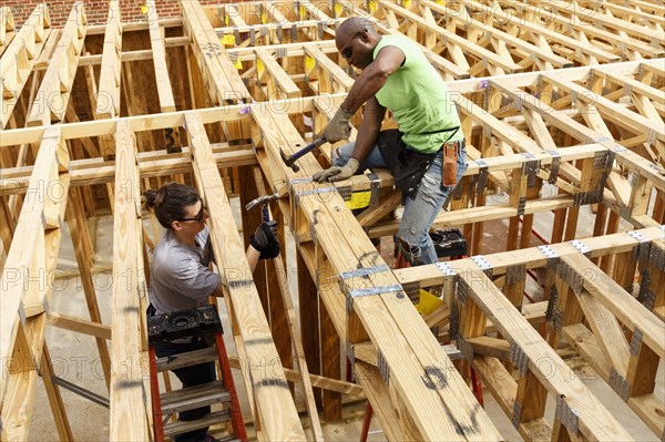 Man and woman hammering frame at construction site