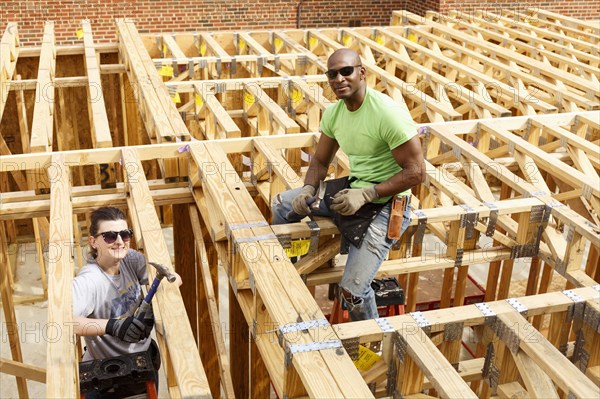 Portrait of man and woman holding hammers at construction site