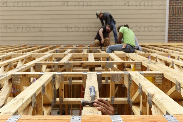 Hand reaching for hammer on the roof at construction site