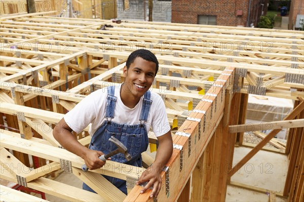 Portrait of mixed race man hammering nail at construction site