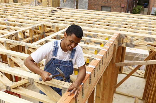 Mixed race man hammering nail at construction site