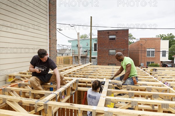 Volunteers hammering nails at construction site