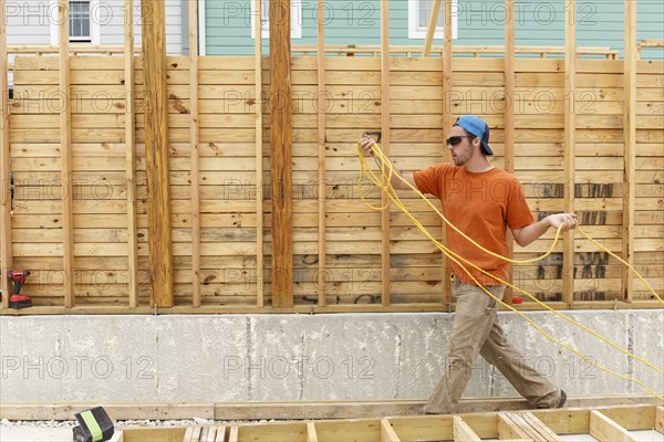 Caucasian man carrying wire at construction site