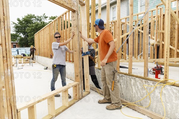 Volunteers holding framed wall at construction site