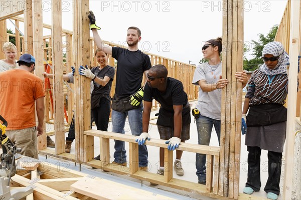 Volunteers holding framed wall at construction site
