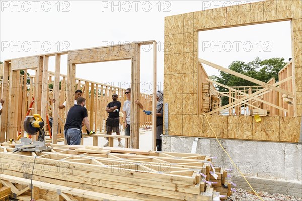 Volunteers holding framed wall at construction site