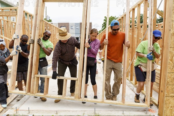 Volunteers lifting wall at construction site