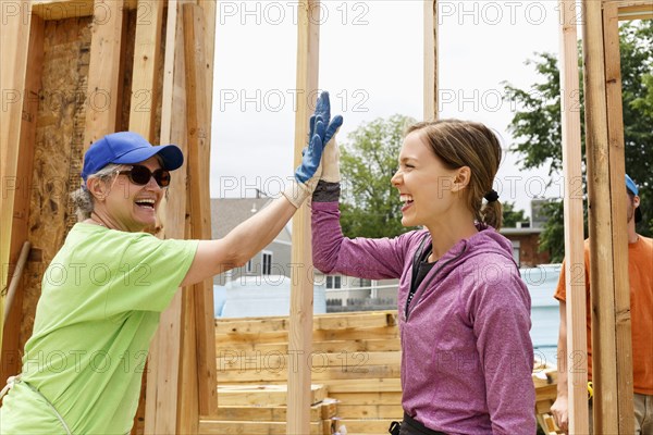 Caucasian volunteers high-fiving at construction site