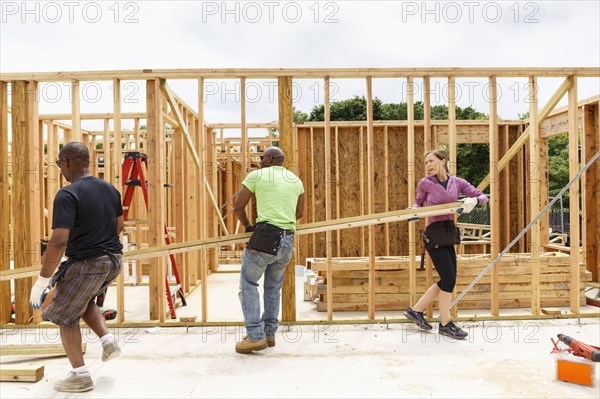 Volunteers carrying lumber at construction site