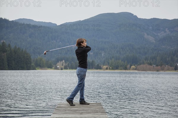 Caucasian woman golfing into lake