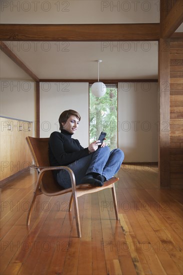 Caucasian woman using cell phone in armchair