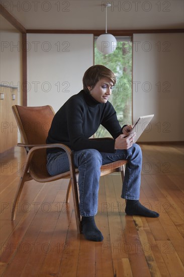 Caucasian woman using tablet computer in armchair