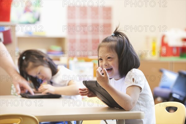 Mixed race Down syndrome student using tablet computer in classroom