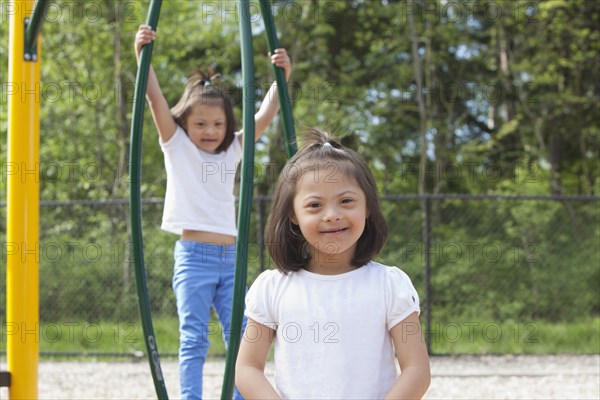 Mixed race Down syndrome girls smiling on playground