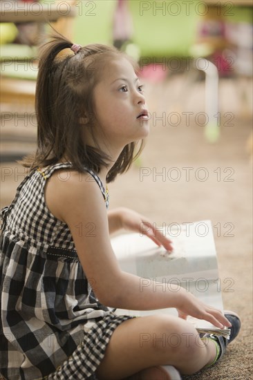 Mixed race Down syndrome student sitting on floor