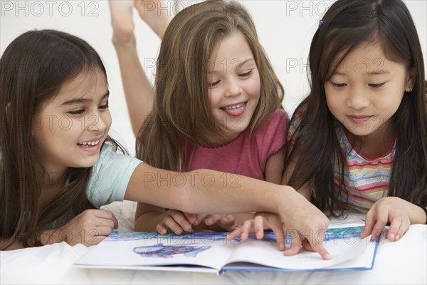 Three young girls reading book