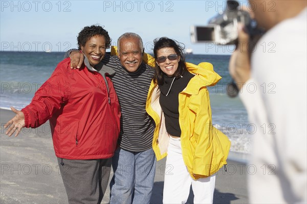 Group of middle-aged friends using video camera at beach