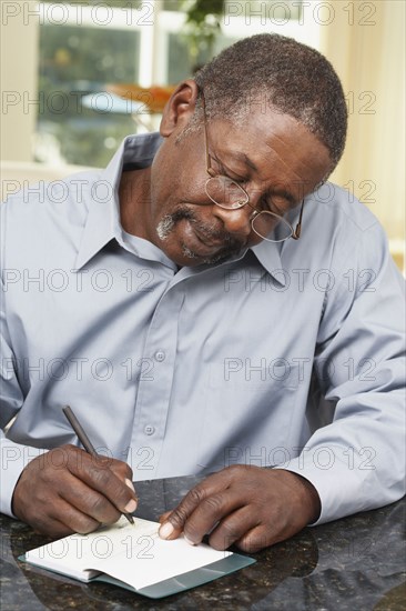 Senior African American man writing check