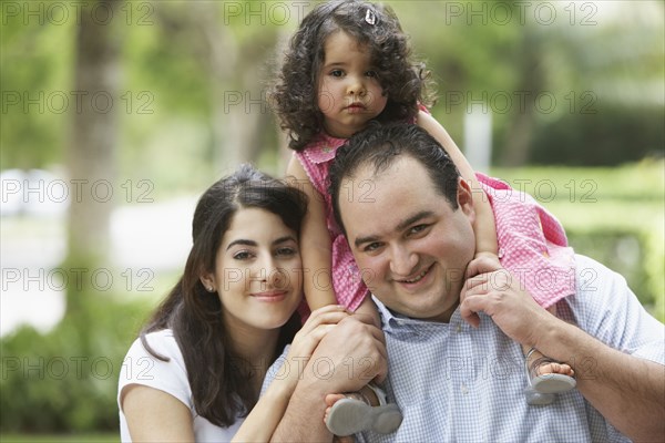 Hispanic father and mother with daughter on shoulders
